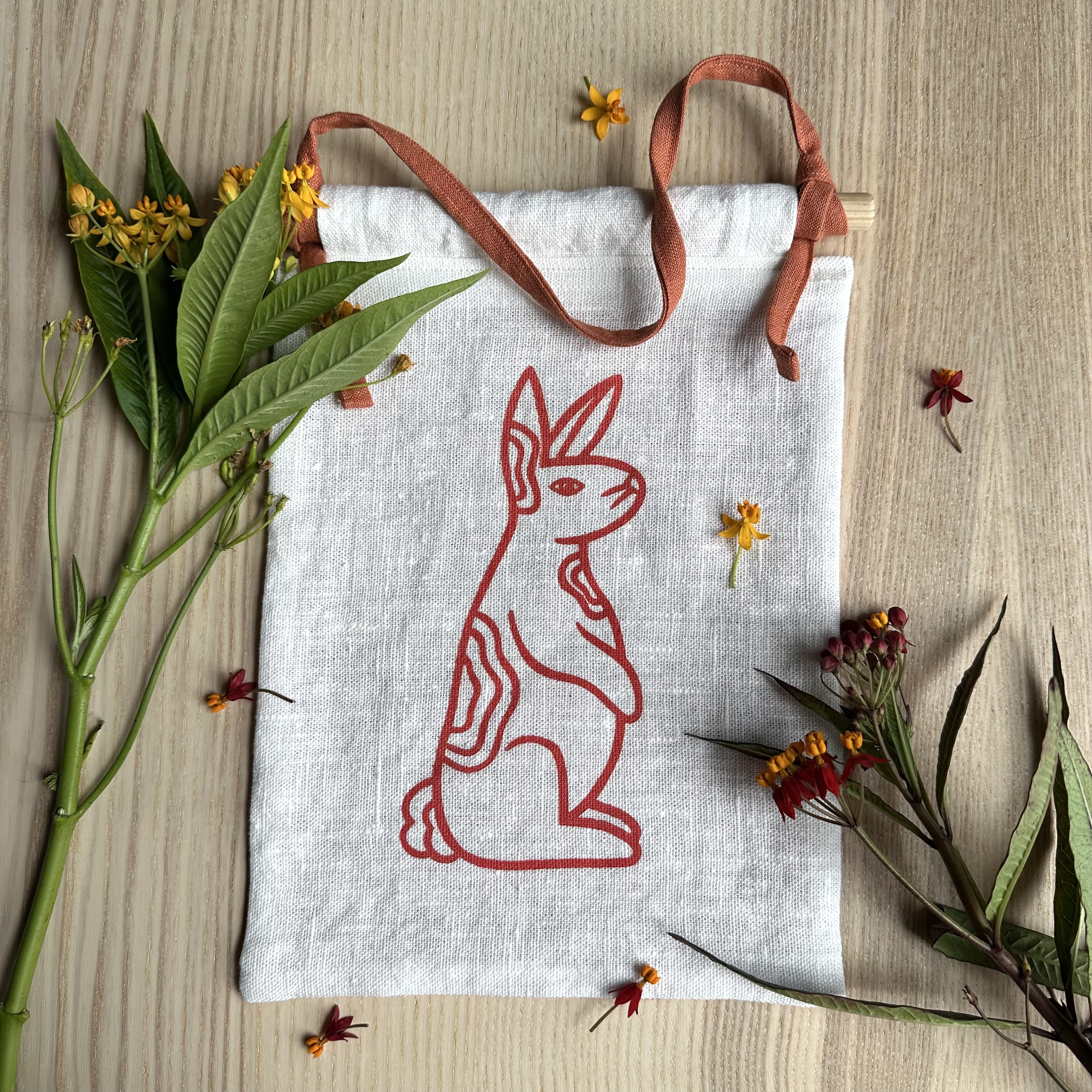 Linen wall-hanging with red rabbit design amongst scattered flowers
